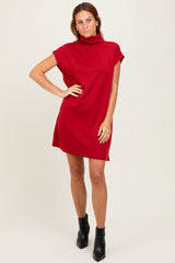 woman wearing a red short sleeve turtleneck dress and black ankle boots