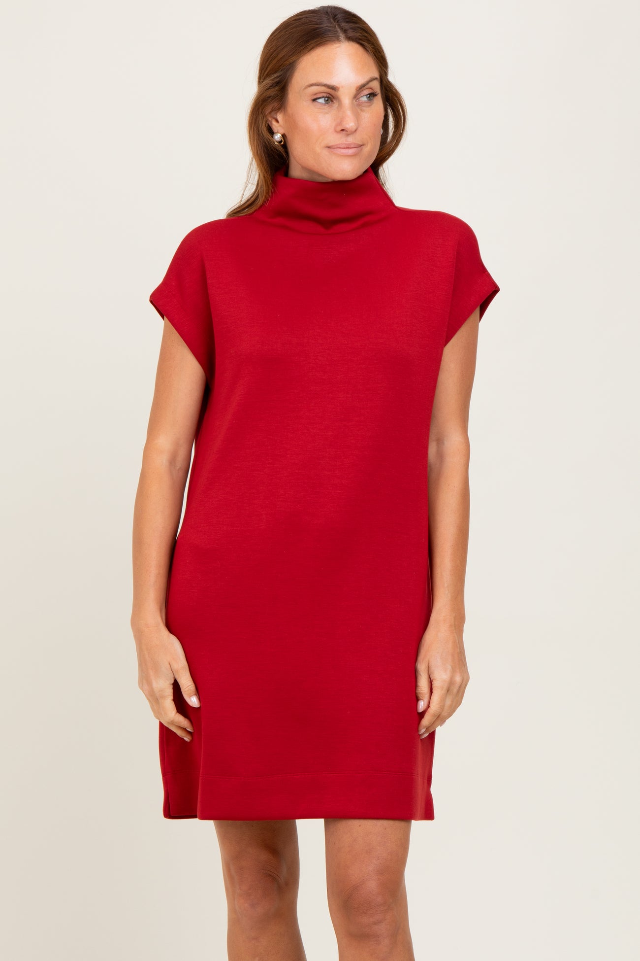 woman wearing a red sleeveless turtleneck dress with a relaxed fit and side slits