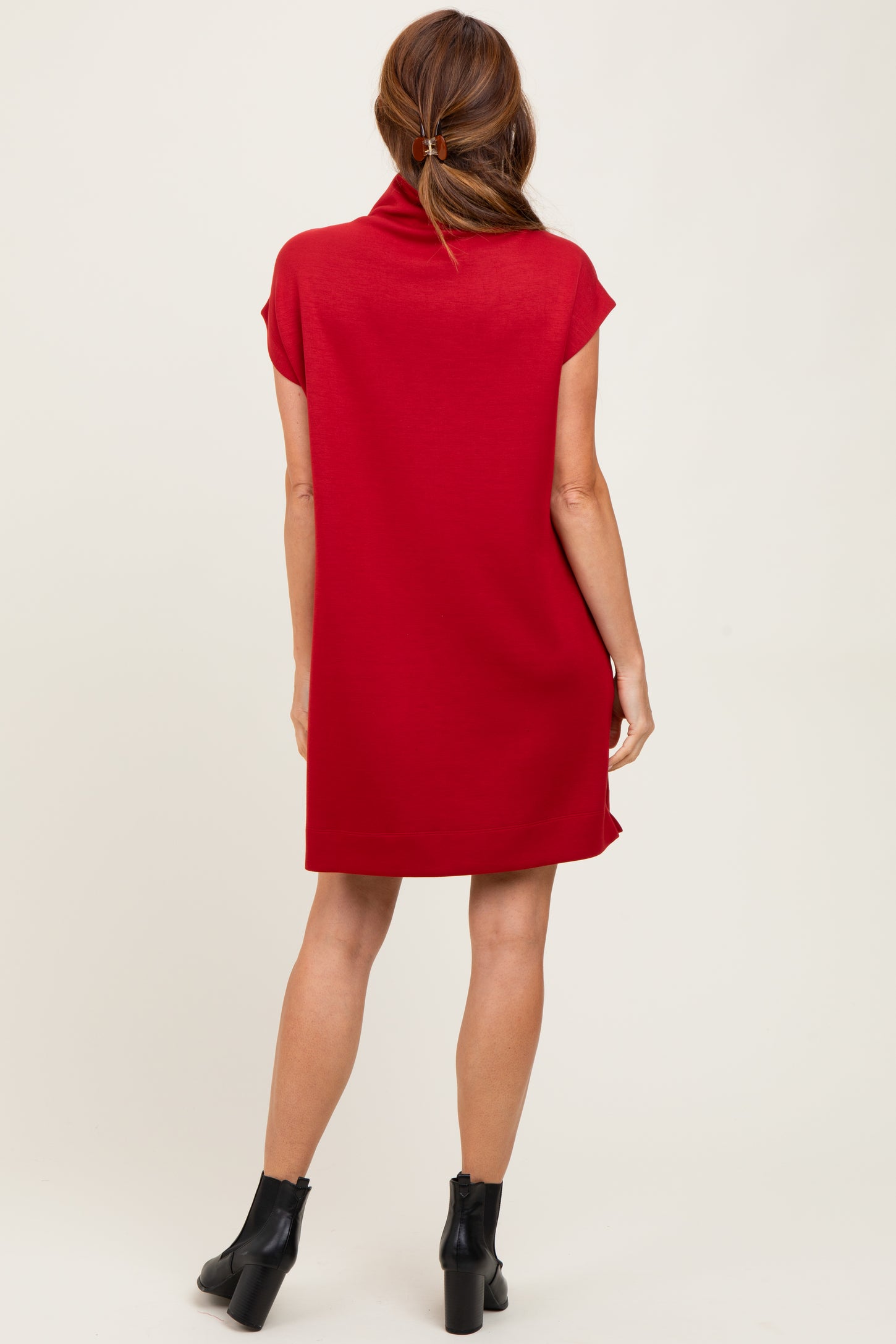 woman wearing a red short sleeve dress with a cowl neck and a relaxed fit, standing with her back to the camera