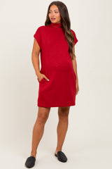 woman wearing a red short sleeve maternity dress with pockets and a relaxed fit, showing a visible baby bump