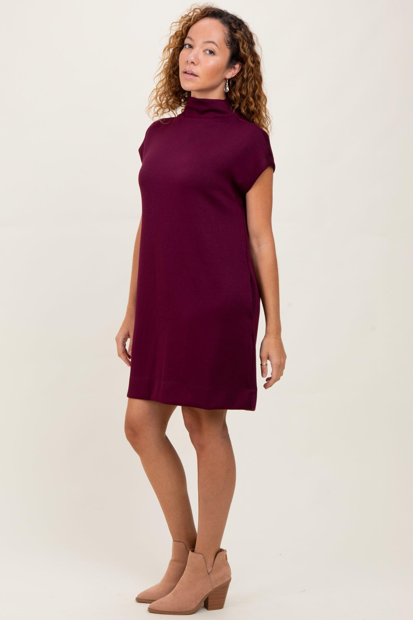 woman wearing a burgundy short sleeve mock neck dress and tan ankle boots
