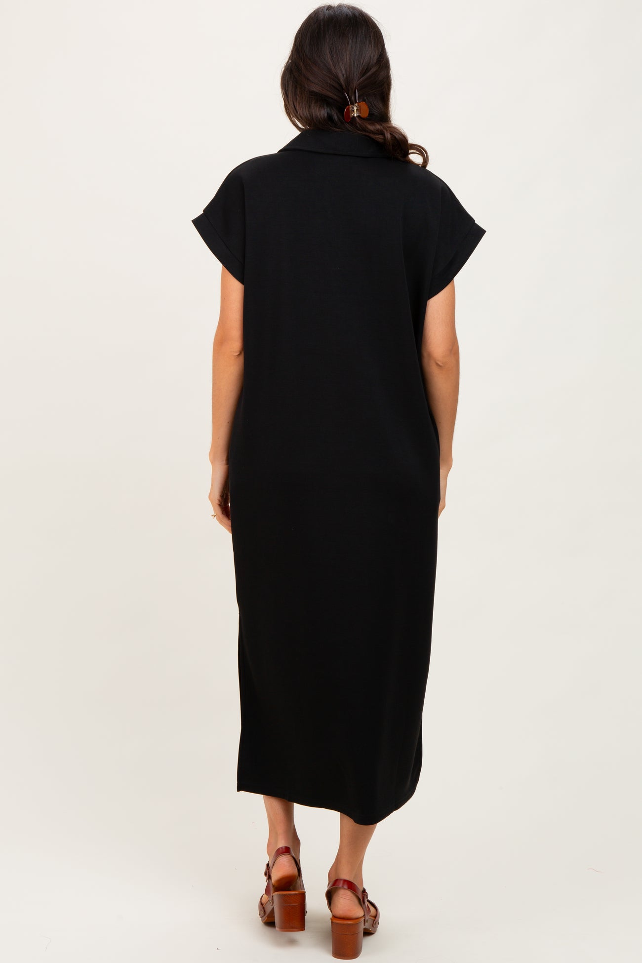 woman wearing a black midi dress with short sleeves, shown from the back, featuring a relaxed fit and side slits