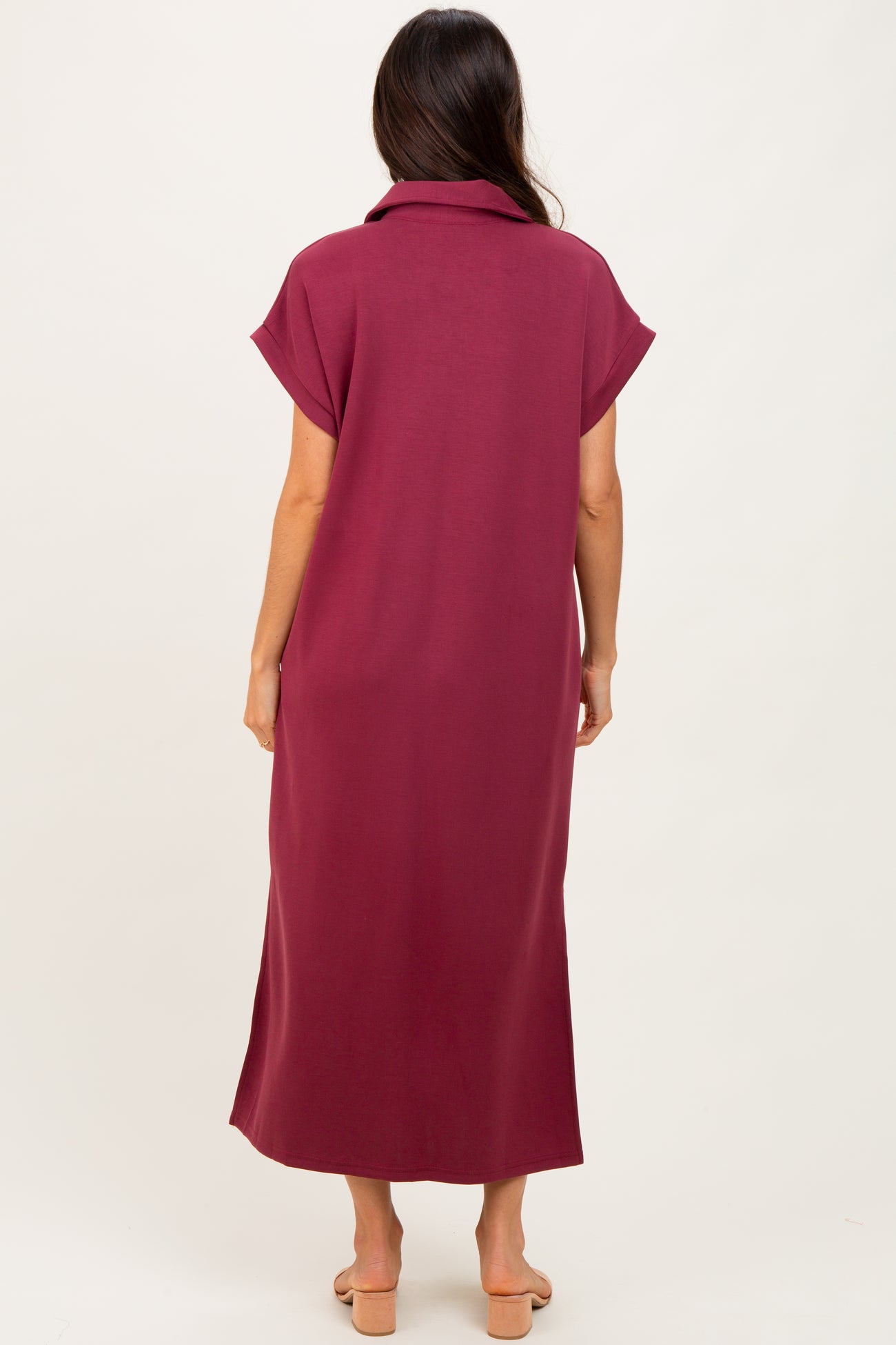 woman wearing a burgundy maxi dress with short sleeves and a collar, shown from the back