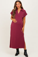woman wearing a burgundy maternity maxi dress with short sleeves and a collar, holding her baby bump