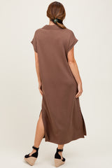 woman wearing a brown short sleeve maxi dress with side slits and a collar, standing with her back to the camera
