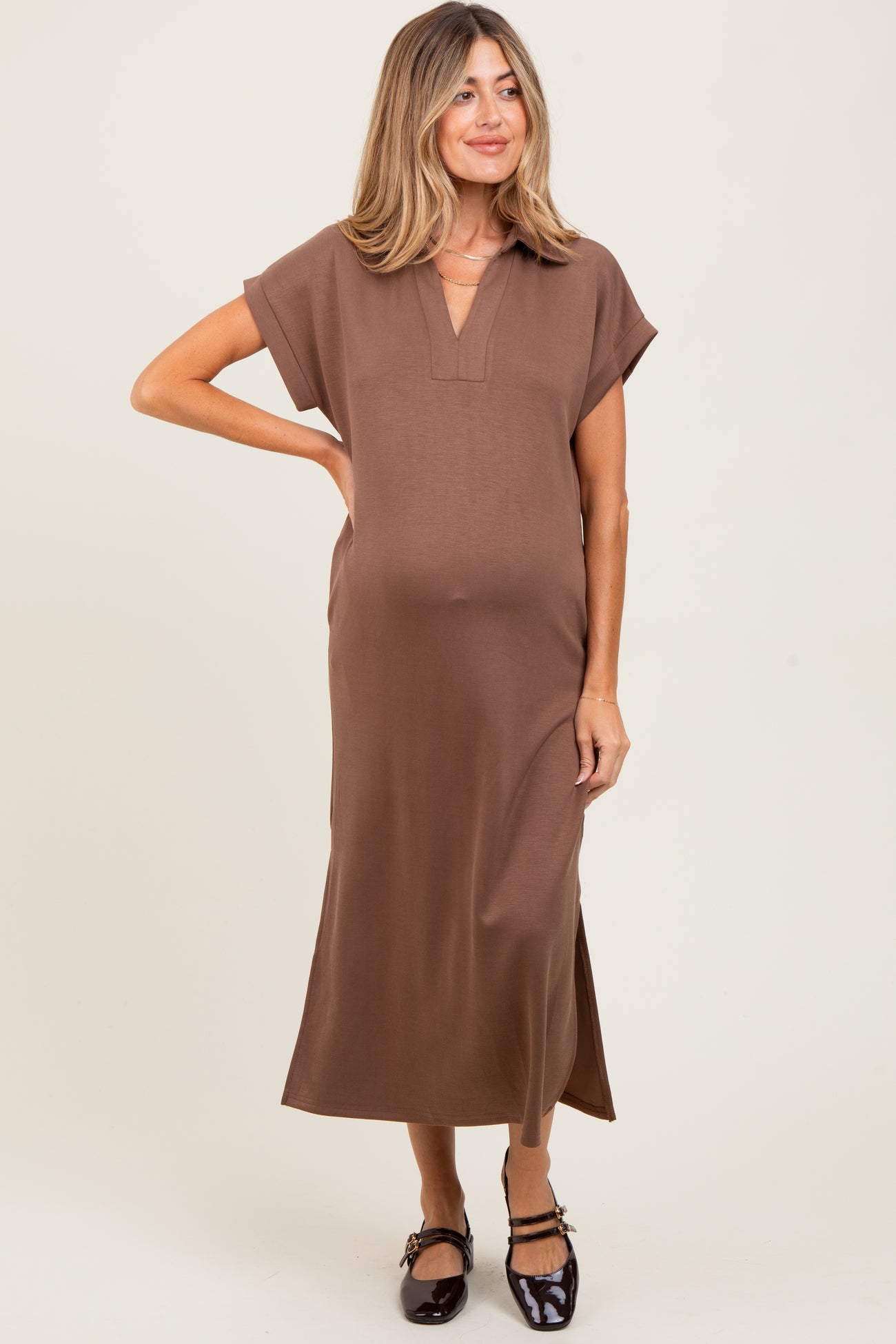 woman wearing a brown short sleeve maternity dress with a v-neck and side slits, showing her baby bump
