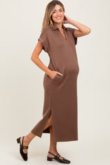 woman wearing a brown maternity polo dress with side slits and pockets, holding her baby bump