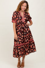 woman wearing a brown floral midi dress with short sleeves and red trim, posing with one hand on her hip