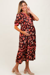 woman wearing a brown floral maternity dress with short sleeves and a tiered skirt, holding her baby bump