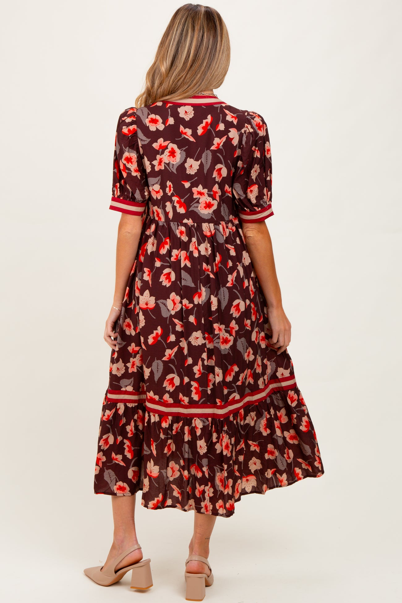 woman wearing a floral brown maternity dress with short sleeves and tiered hem, showing a baby bump from the back