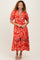 woman wearing a red floral midi dress with puff sleeves and a tiered skirt