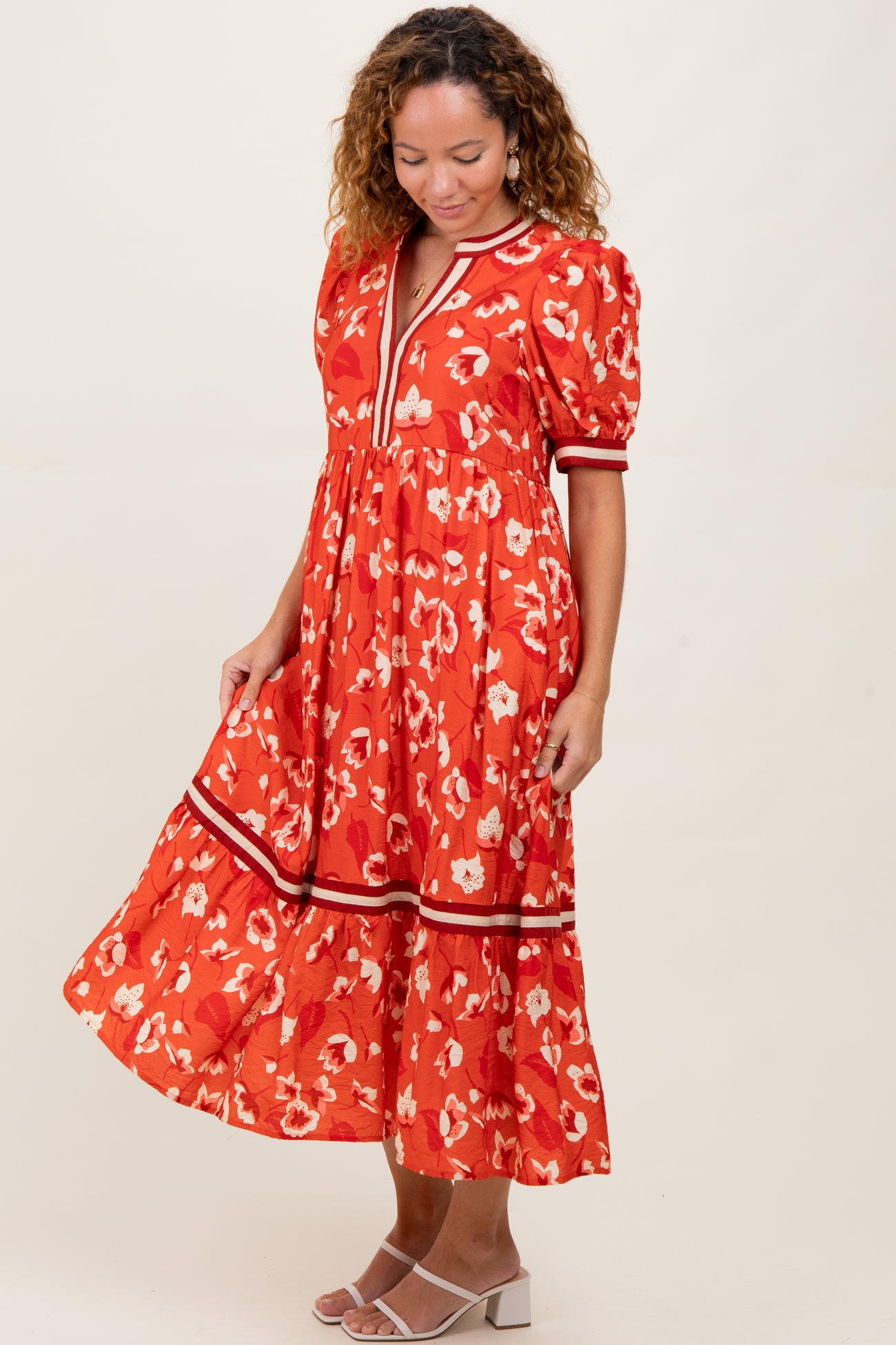 woman wearing a red floral midi dress with puff sleeves and a tiered skirt