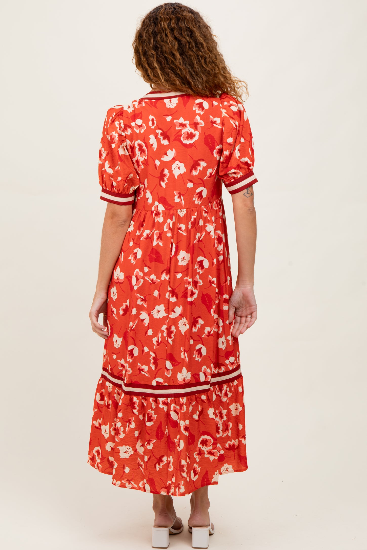 woman wearing a red floral maxi dress with puff sleeves and contrasting trim, showing the back view