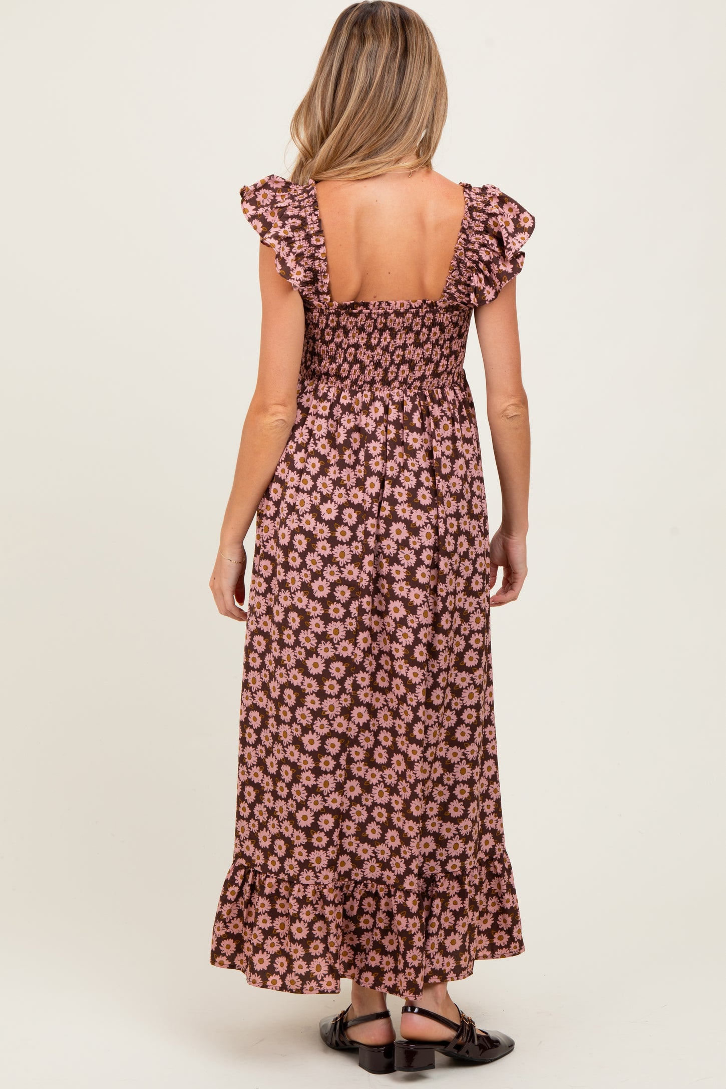 woman wearing a floral print maternity maxi dress with ruffle sleeves and a tiered hem, showing her back