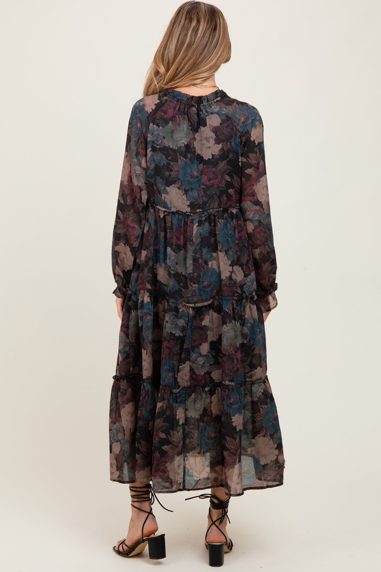woman wearing a flowy long sleeve floral maternity dress with a tiered skirt and a gathered neckline, styled with heeled sandals
