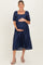 woman wearing a navy blue maternity dress with puff sleeves and a square neckline, holding her baby bump