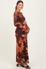 woman wearing a long sleeve brown floral maternity dress and holding her baby bump