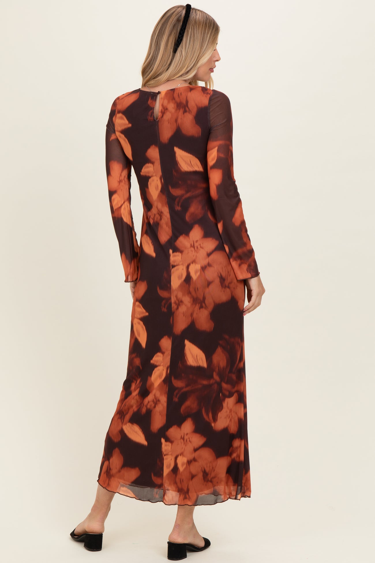 woman wearing a long sleeve floral maxi dress in shades of brown and orange, back view