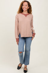 woman wearing a blush pink waffle knit sweater with rust accents and distressed light blue flared jeans