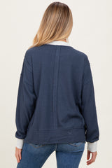 woman wearing a navy blue maternity sweatshirt with a relaxed fit and contrasting cuffs, seen from the back