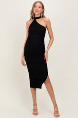 woman wearing a black halter neck maternity dress with ruching and a side slit, showcasing her baby bump