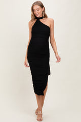 woman wearing a black halter neck maternity dress with ruched detailing, showcasing her baby bump