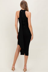 woman wearing a black ruched maternity dress with a tie-back detail and a knee-length hem