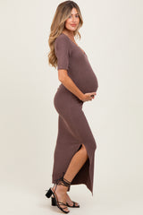 woman wearing a brown ribbed maternity dress with a side slit and holding her baby bump