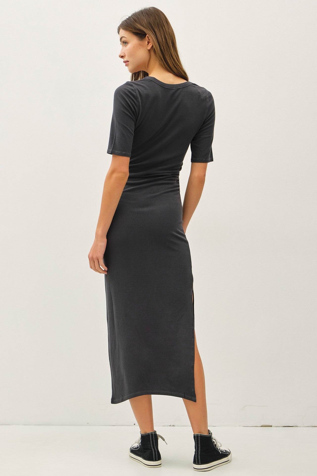 woman wearing a charcoal gray midi dress with short sleeves and a side slit, viewed from the back