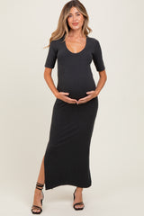 woman wearing a black short sleeve maternity dress with a scoop neckline and side slit, holding her baby bump