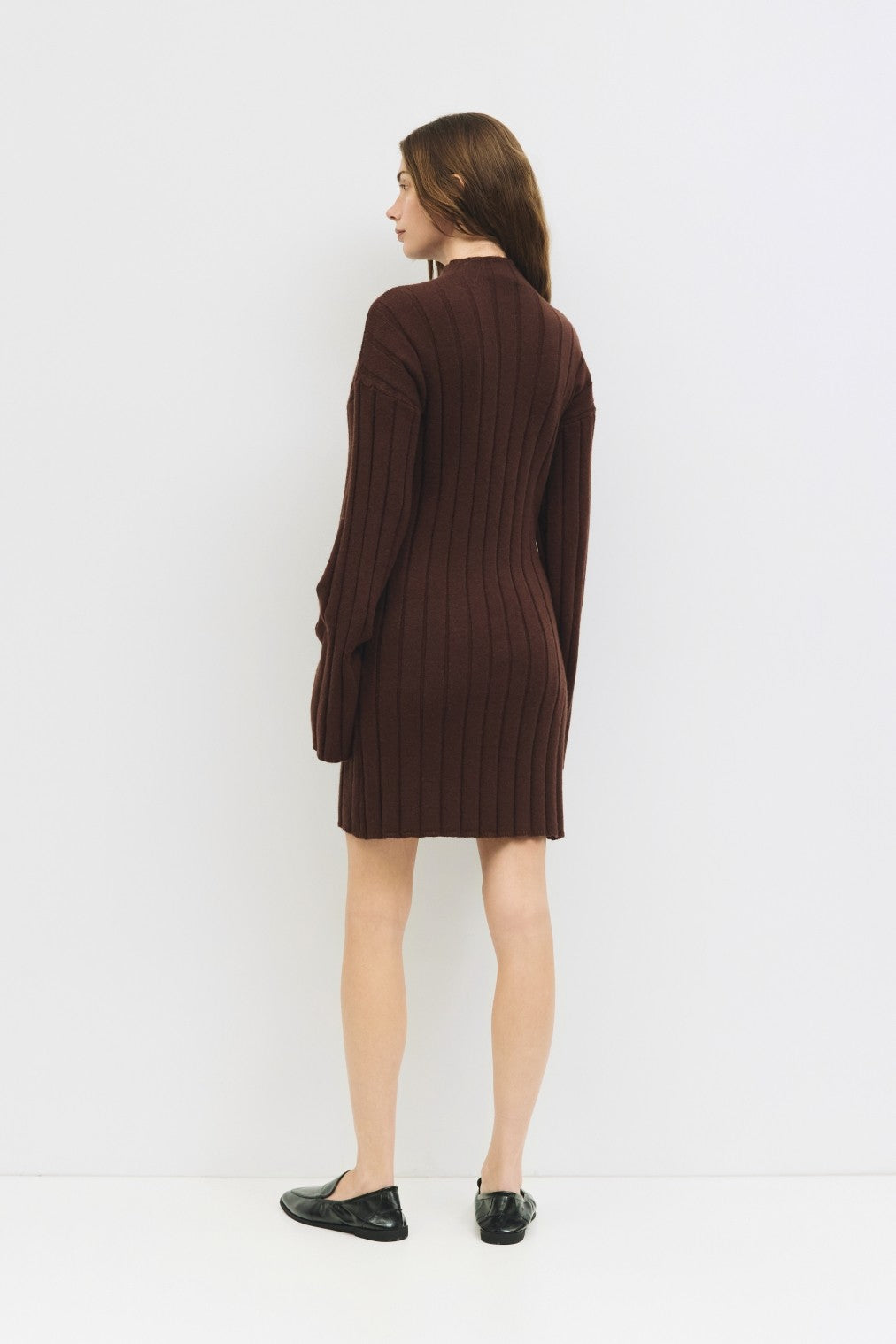 woman wearing a brown ribbed sweater dress, showing the back view with long sleeves and a relaxed fit