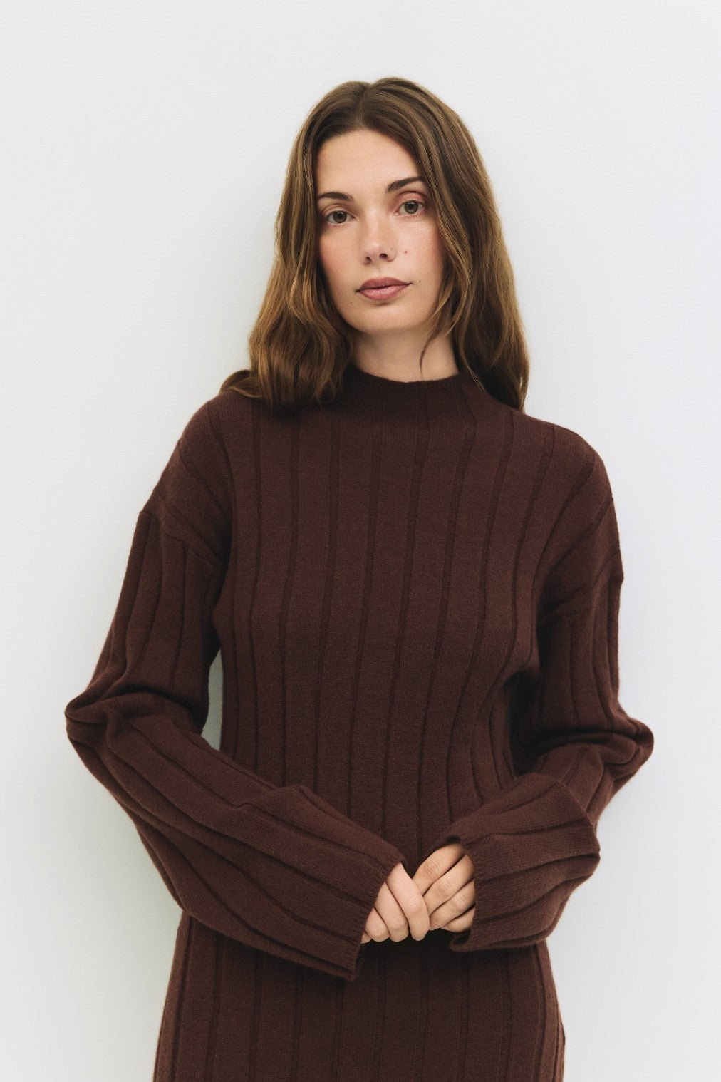 woman wearing a brown ribbed knit long sleeve sweater with a high neckline and wide sleeves