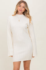 woman wearing a cream ribbed long sleeve mini dress with a high neckline and flared sleeves