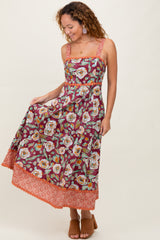 woman wearing a burgundy floral maxi dress with lace trim and spaghetti straps, posing with a smile