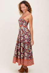 woman wearing a burgundy floral maxi dress with a halter neck and orange patterned hem