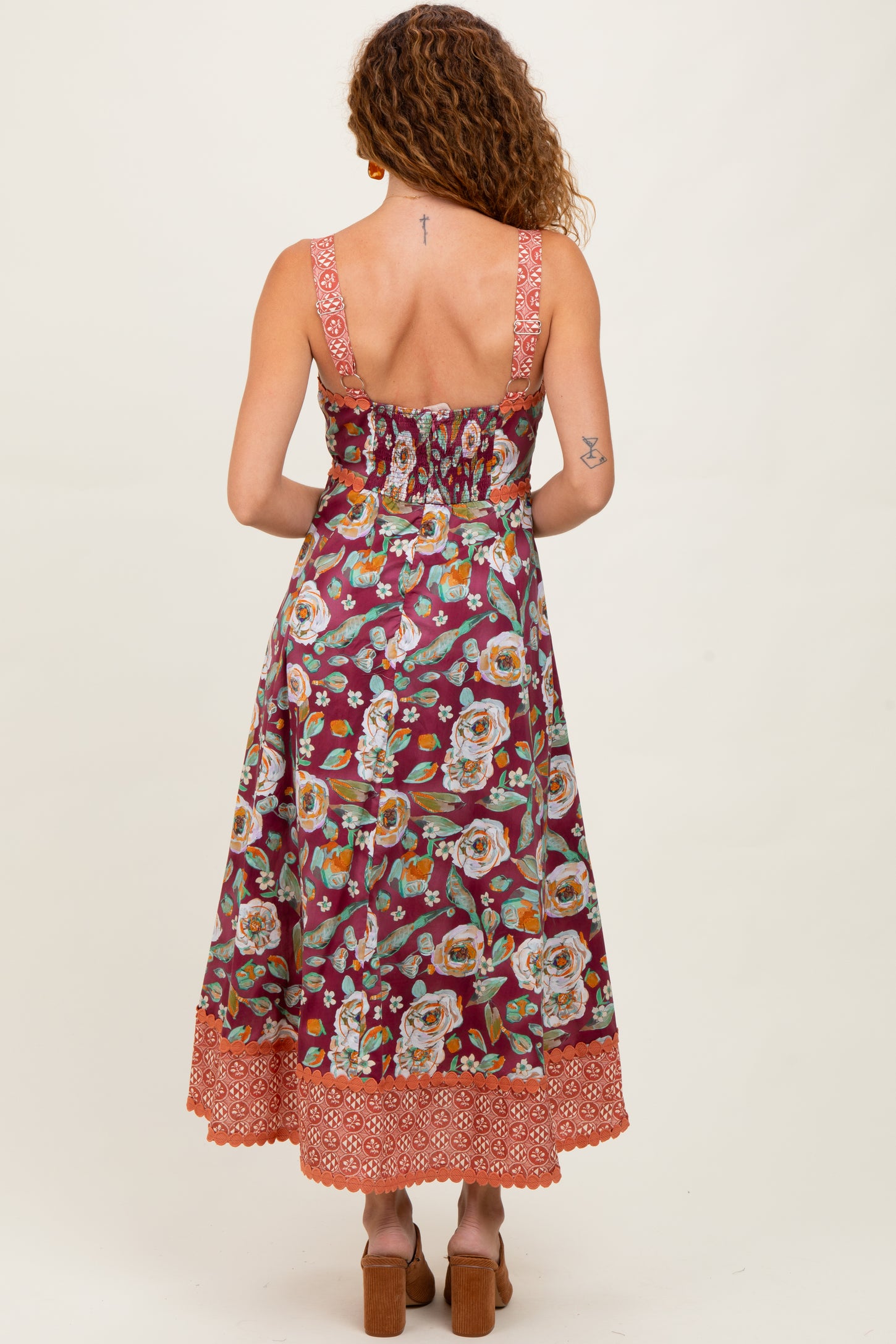 woman wearing a floral print maxi dress with a fitted bodice and tiered hem, showing the back view