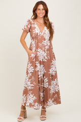 woman wearing a brown floral maxi dress with a v-neckline and short sleeves, featuring pockets and a relaxed fit