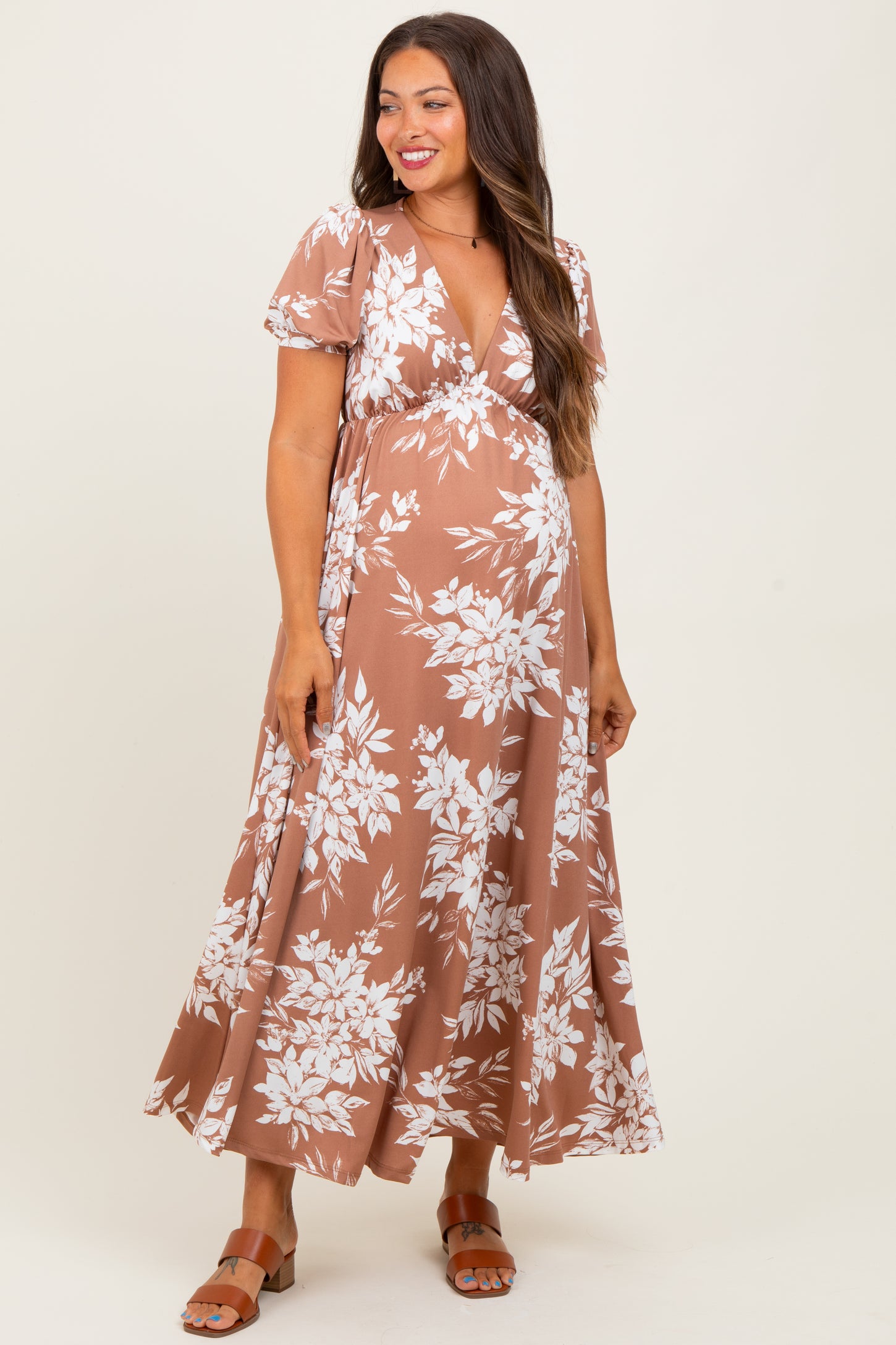 woman wearing a brown floral maternity maxi dress with a deep v-neck and short sleeves, showing her baby bump