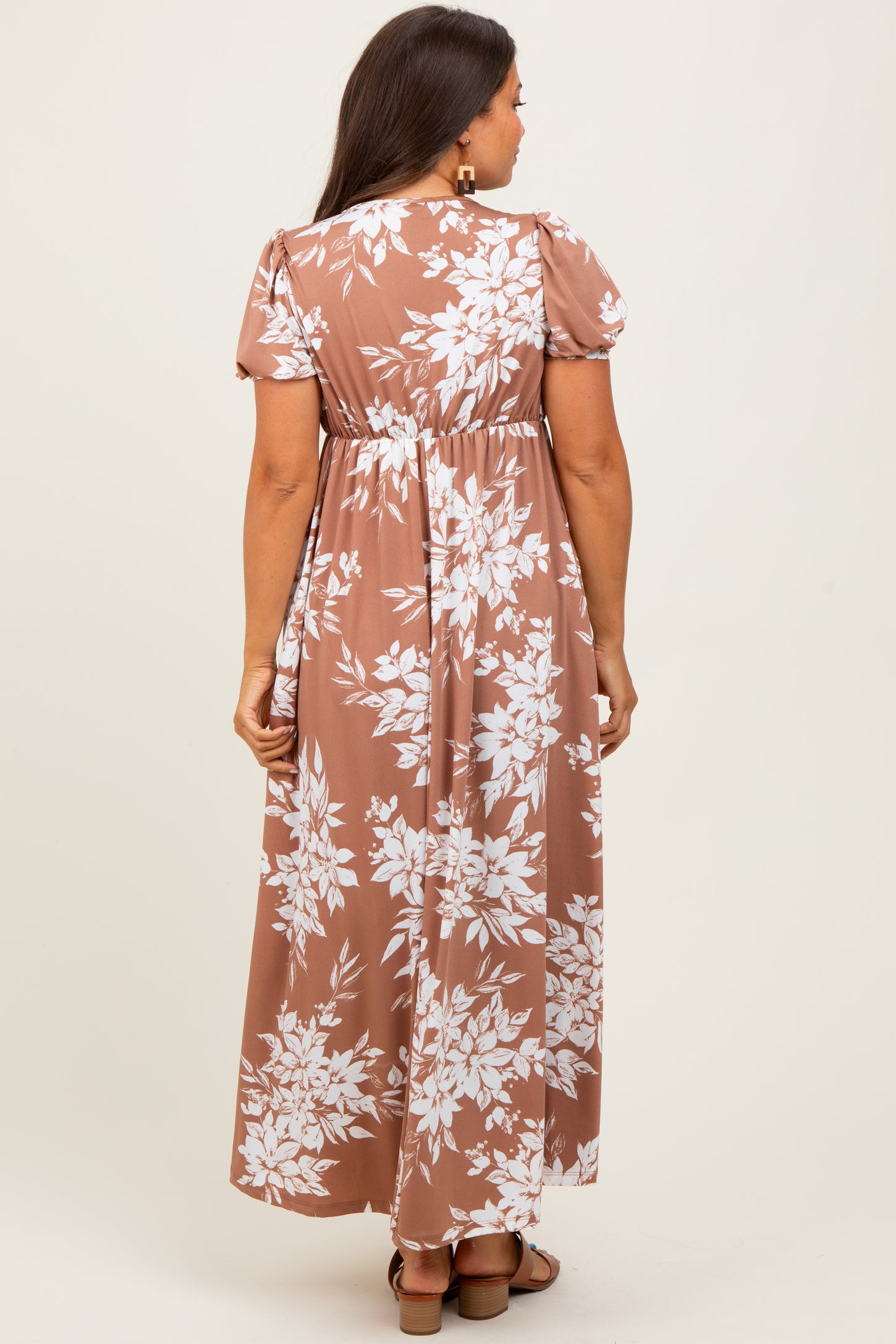 woman wearing a brown floral maternity dress with short puff sleeves and a flowy maxi length, showing the back view