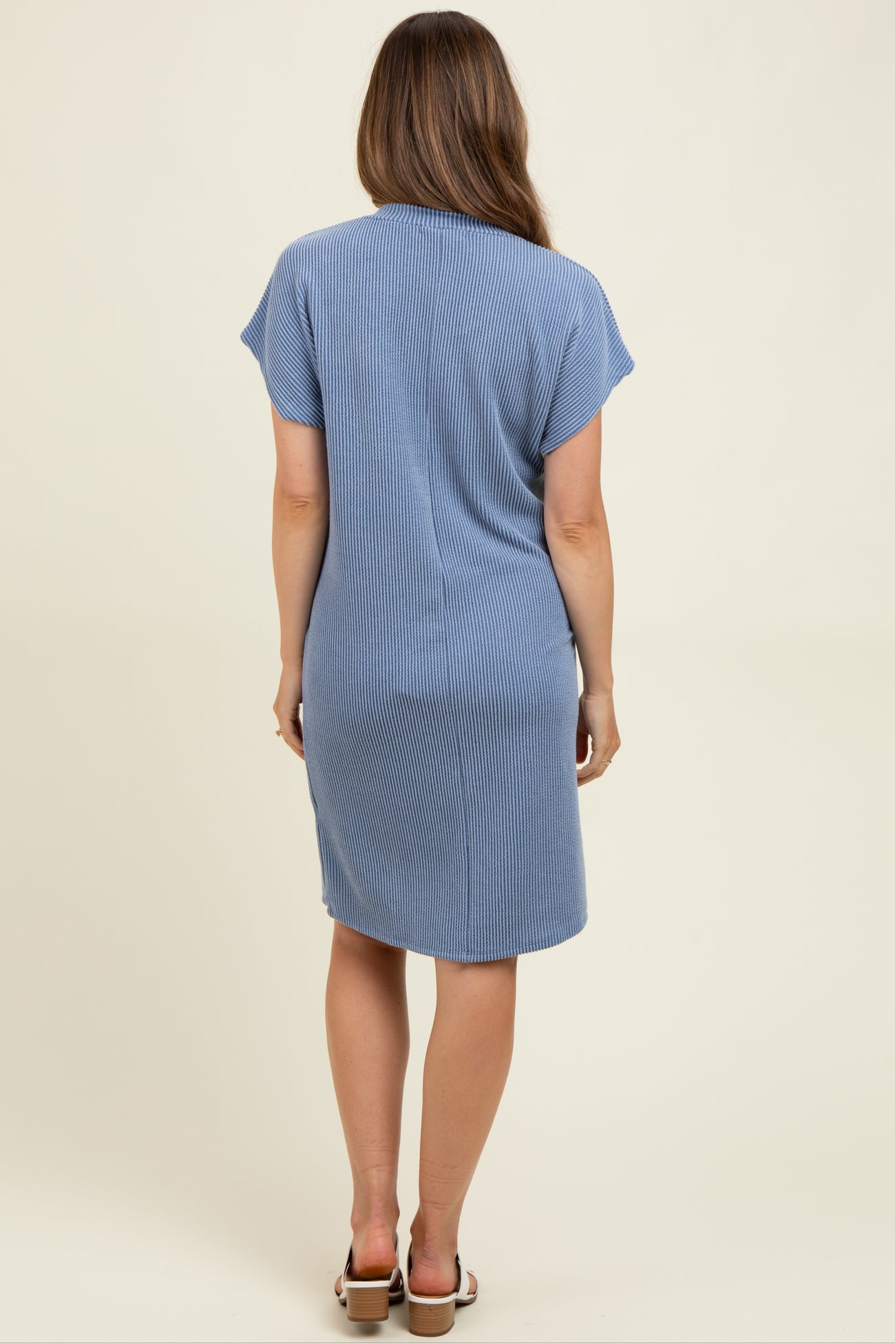 woman wearing a light blue ribbed maternity dress, seen from the back, with short sleeves and a relaxed fit