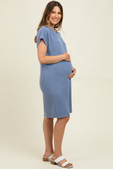woman wearing a light blue ribbed maternity dress and holding her baby bump