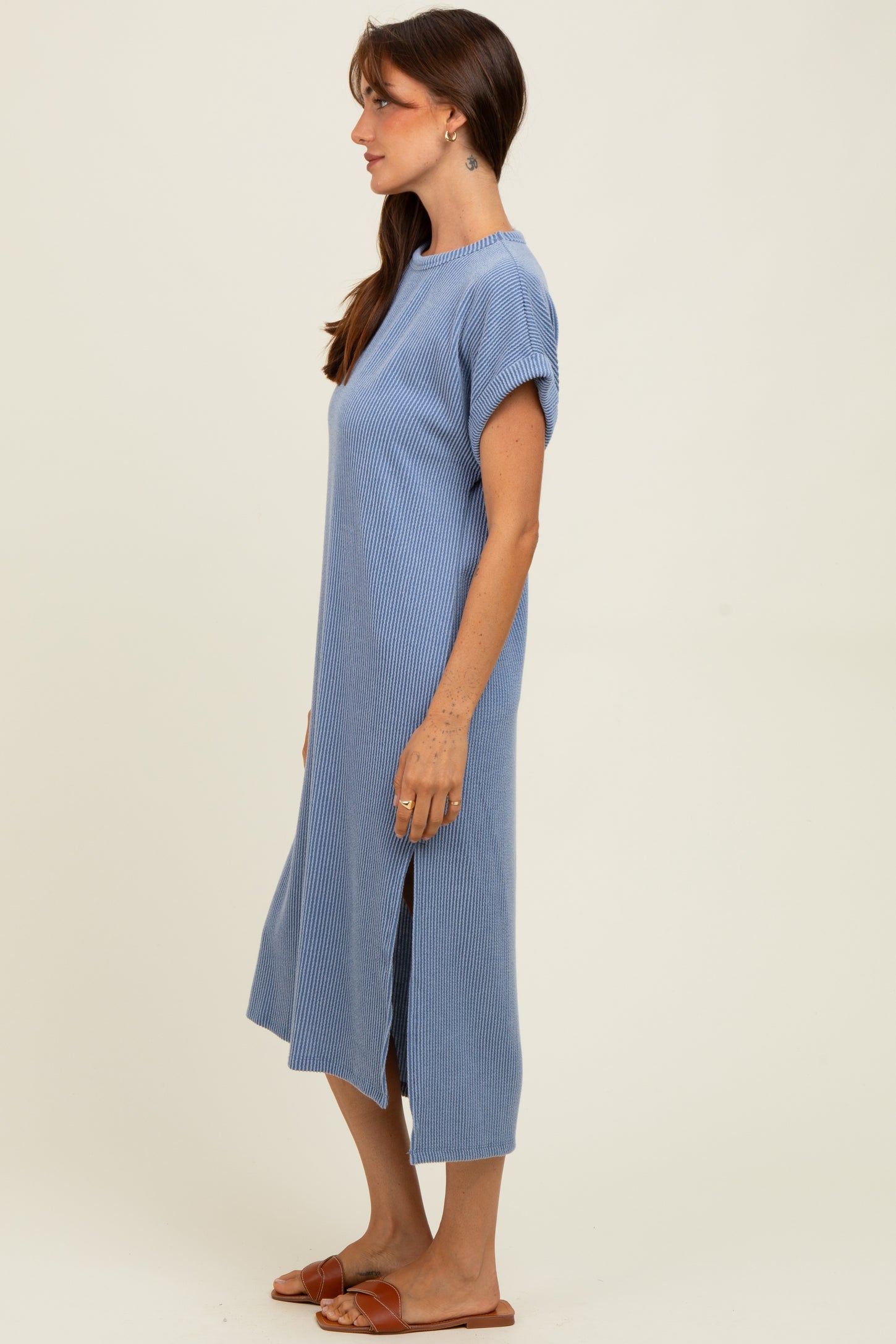 woman wearing a light blue ribbed midi dress with short sleeves and side slits, standing against a neutral background
