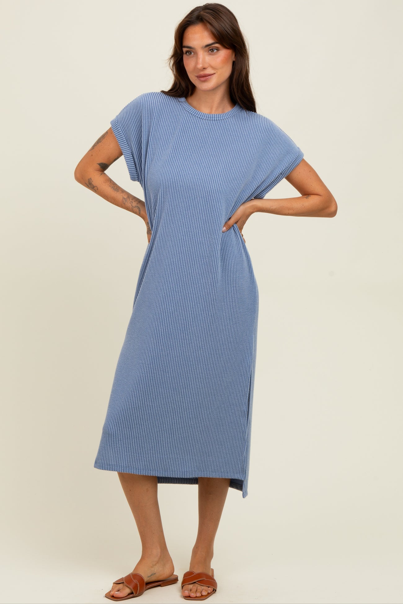 woman wearing a blue striped midi dress with cap sleeves and side slits, styled with flat sandals