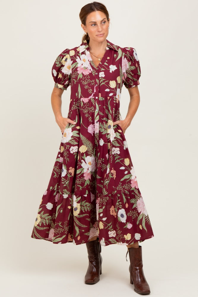woman wearing a burgundy floral maxi dress with puff sleeves and pockets, standing in brown ankle boots