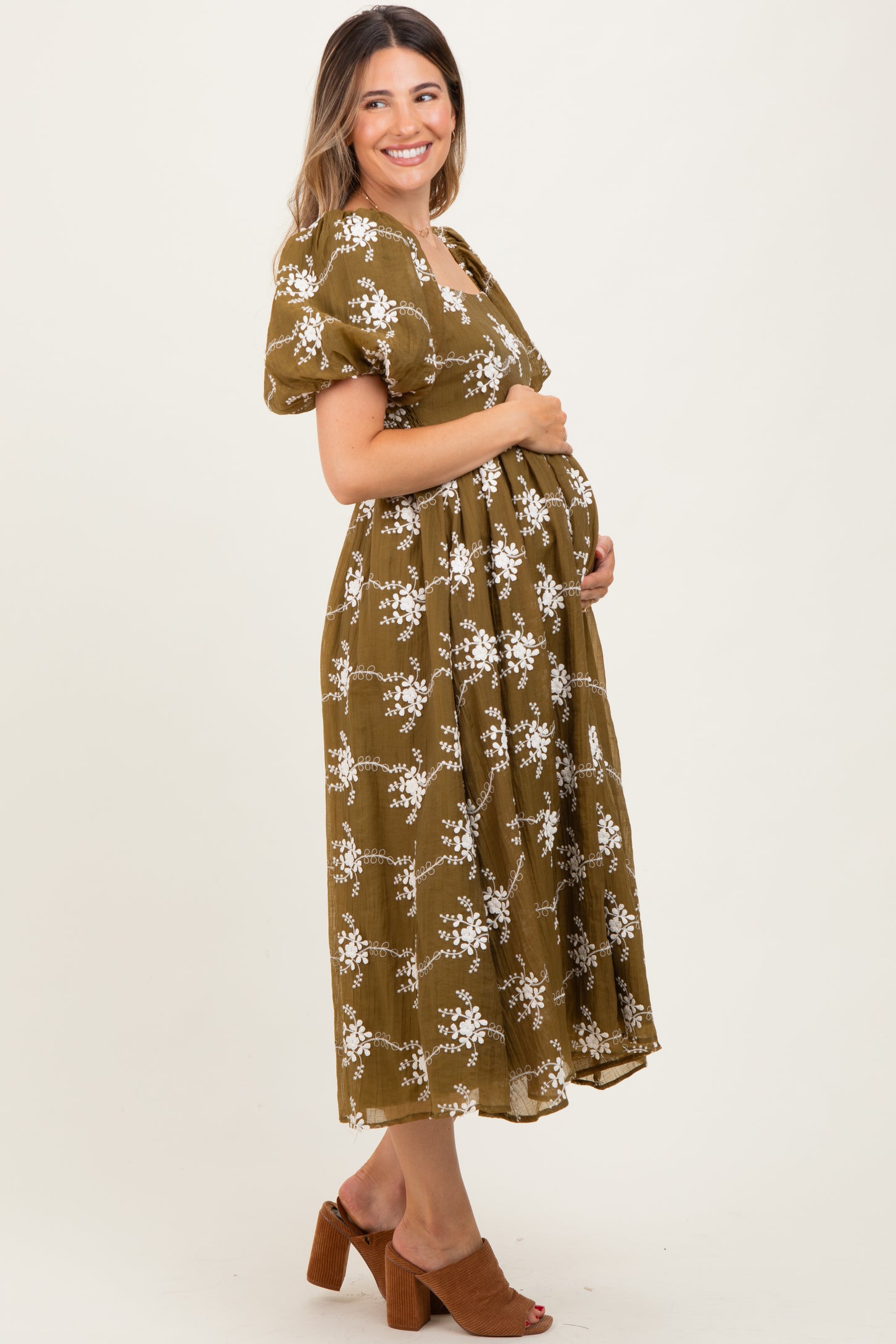woman wearing a brown floral maternity dress and holding her baby bump