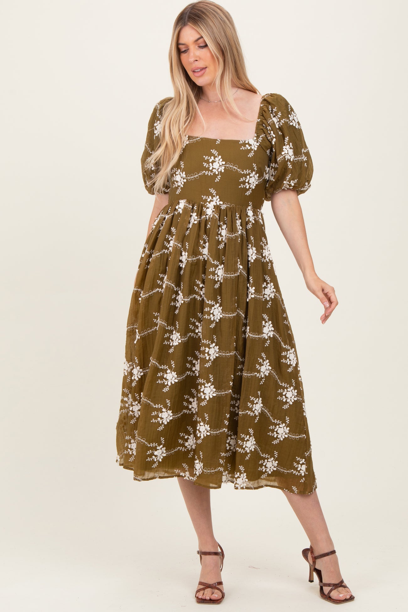 woman wearing an olive green floral midi dress with puff sleeves and a square neckline