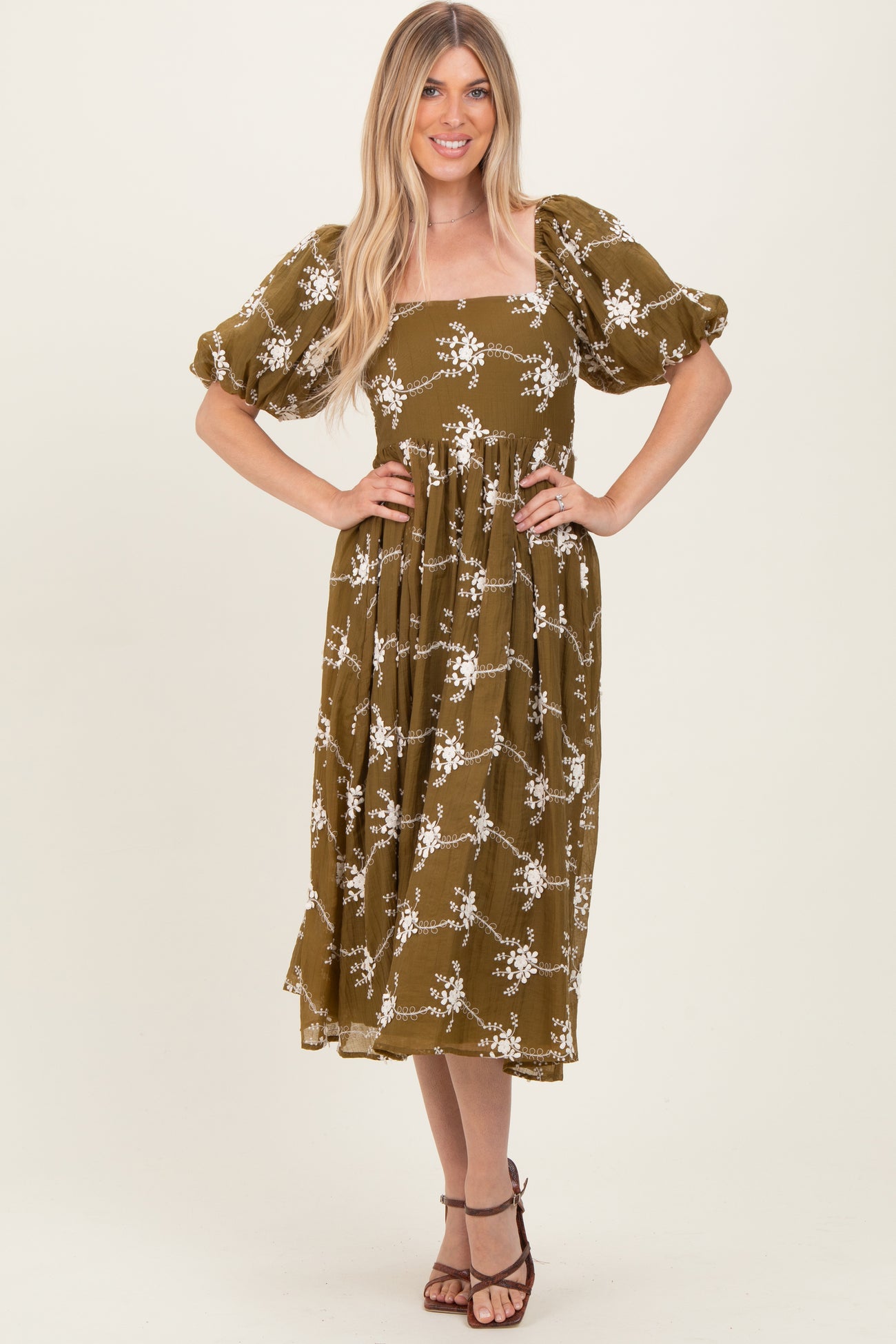 woman wearing an olive green floral midi dress with puff sleeves and a square neckline