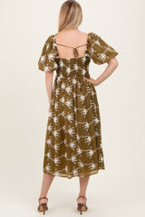 woman wearing an olive green floral print midi dress with puff sleeves and an open back