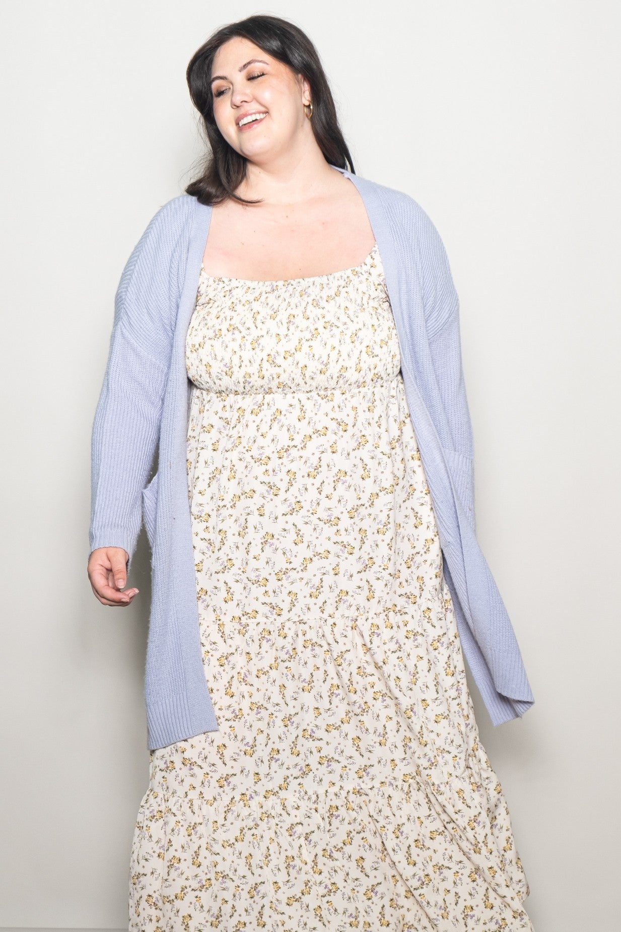 woman wearing a white floral maxi dress and a light purple long cardigan with pockets