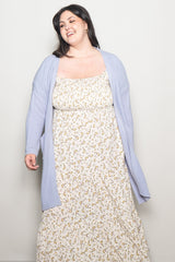 woman wearing a white floral maxi dress and a light purple long cardigan with pockets